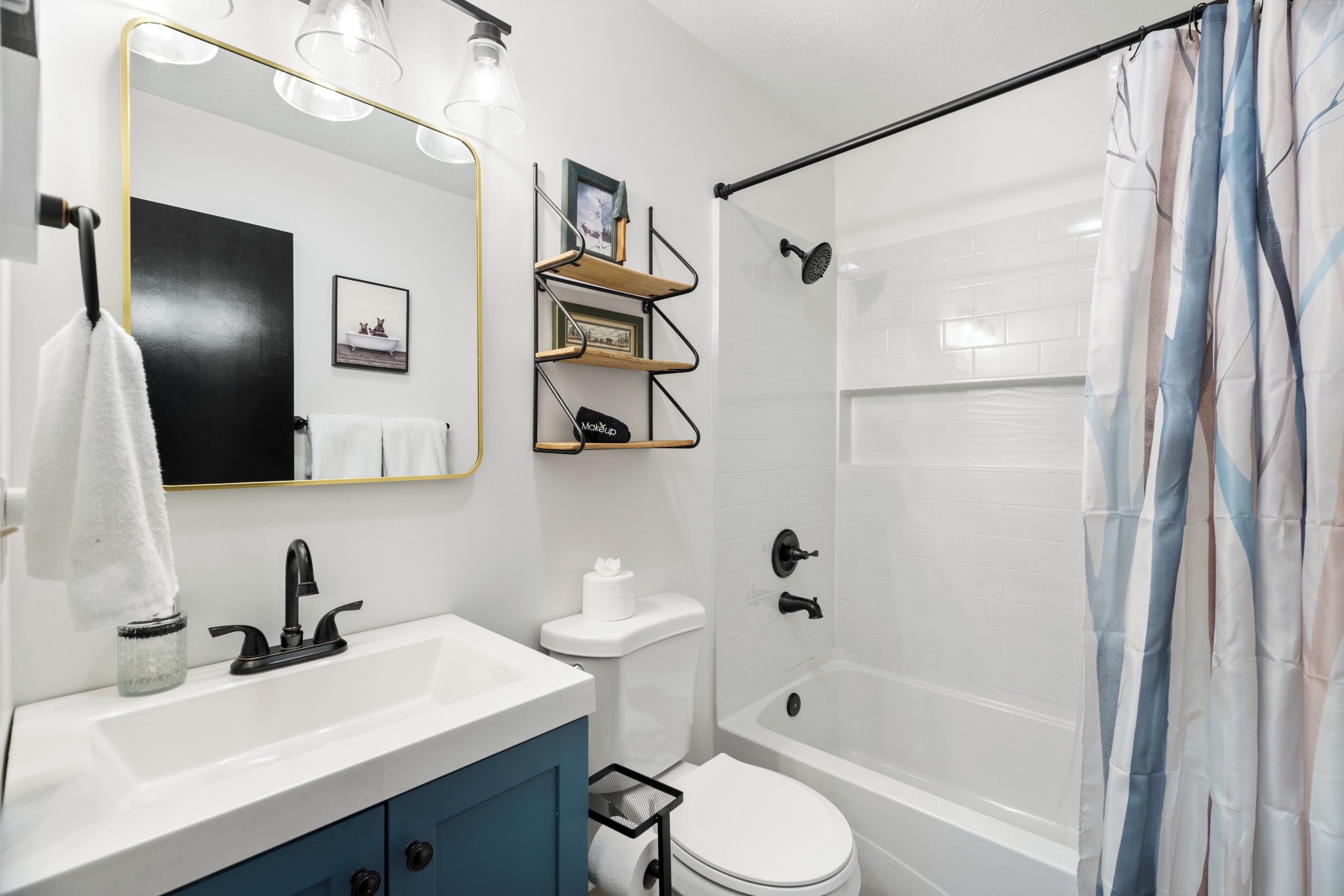 A bathroom with a white sink, black faucet, white toilet, and a shower with a glass door.