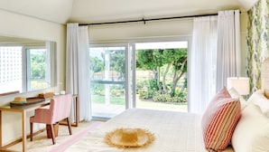 Ein Schlafzimmer mit einem großen Bett, einem Schreibtisch und einem Stuhl, einem Fenster mit Vorhängen und Blick ins Freie.