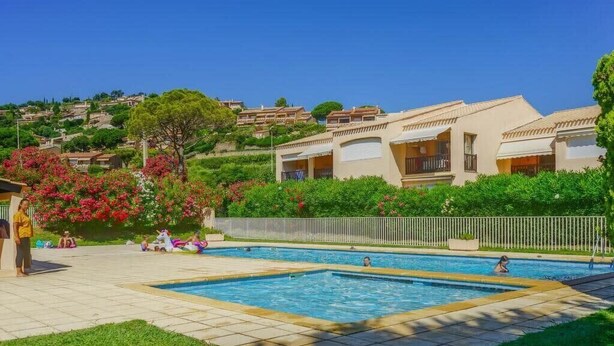 A swimming pool area with a view of hillside houses, a grassy lawn, and a fence. - Direct access to the beach + residence with swimming pool (Le Lavandou)