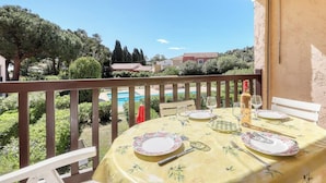 A balcony with a table set for two, overlooking a swimming pool and greenery. - Direct access to the beach + residence with swimming pool (Le Lavandou)