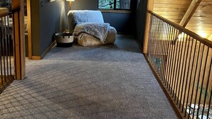 Makuuhuone, jossa on suuri ikkuna, sänky, yöpöytä ja lamppu.