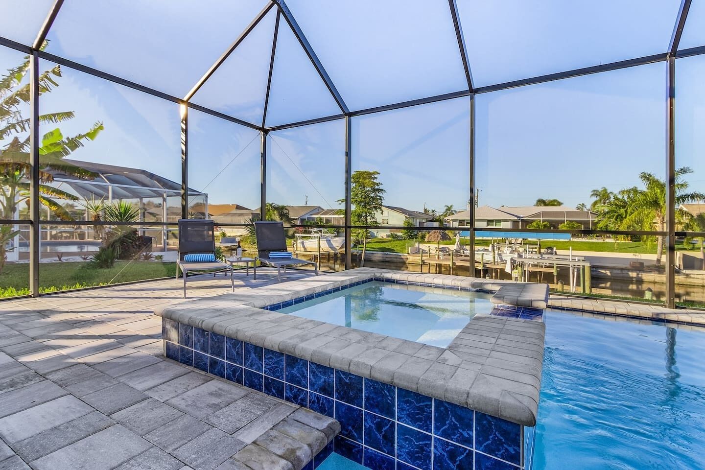 Een zwembadgedeelte met een jacuzzi, ligbedden en een glazen structuur.