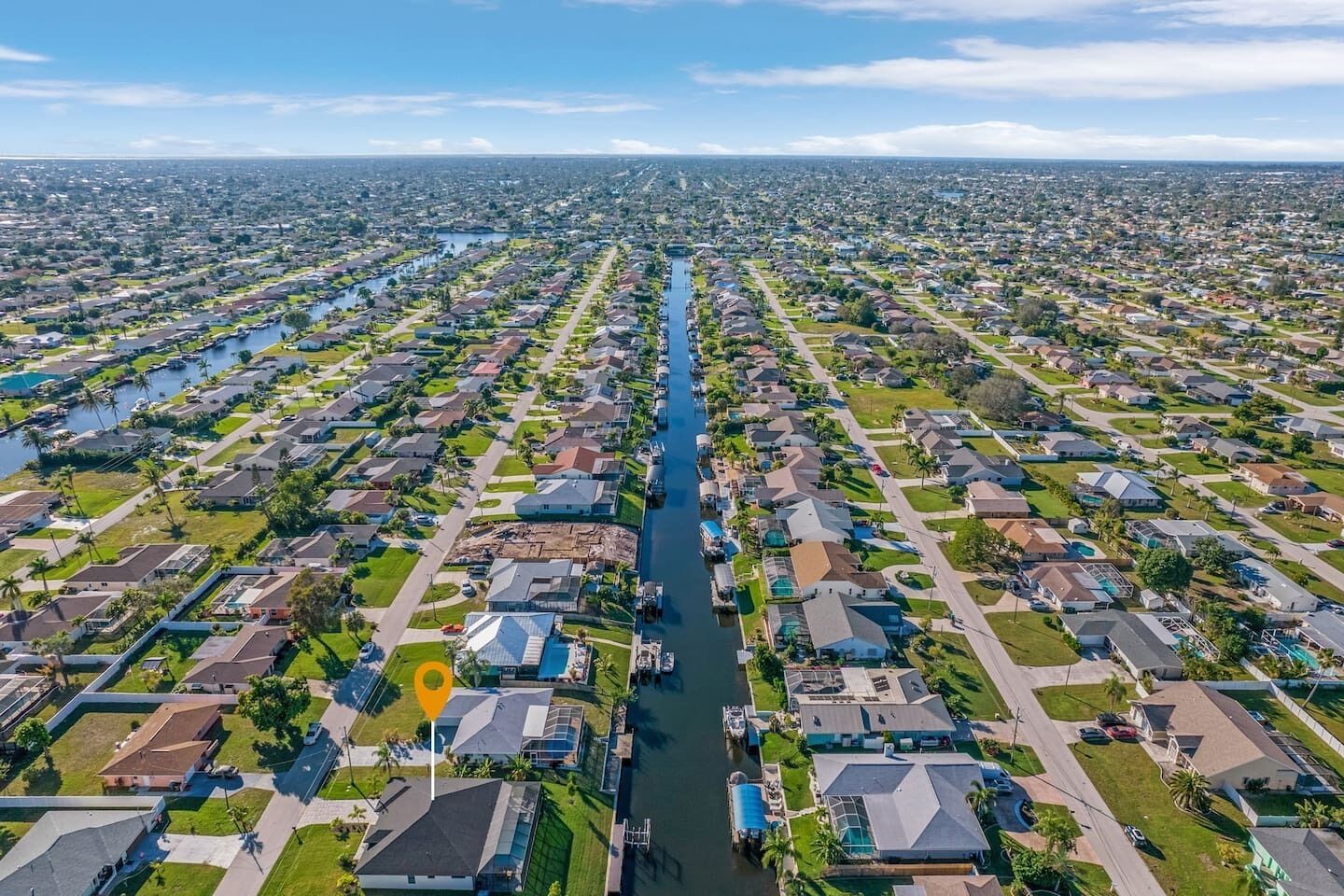 An aerial view of a residential area with houses arranged in rows along a central waterway.