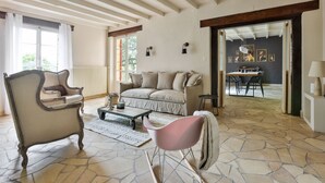 Una sala de estar con sofá, sillones, una mesa de centro y un comedor con sillas y una mesa.