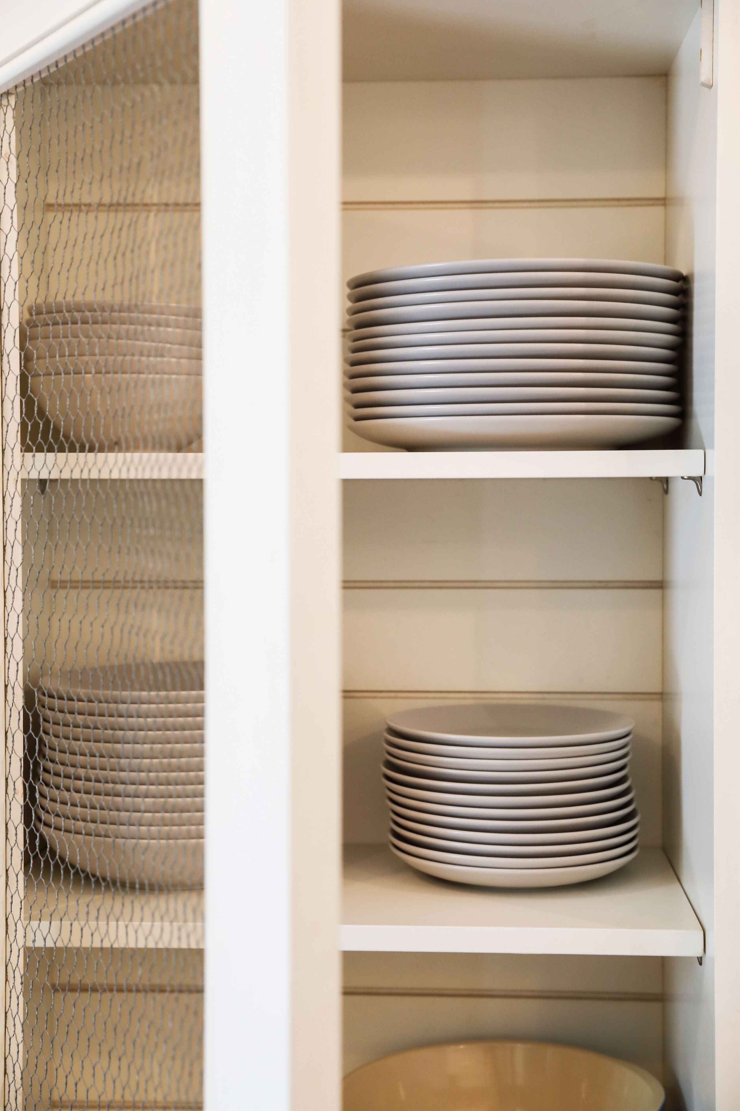 A storage cabinet with shelves holding neatly stacked plates.
