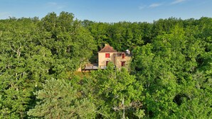 Un edificio de piedra con techo rojo, rodeado de un bosque verde frondoso.
