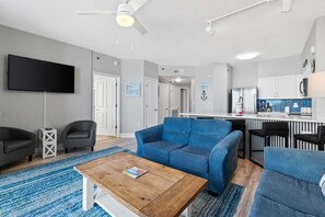 Una sala de estar moderna con un sofá azul, una mesa de centro de madera y un televisor de pantalla plana.