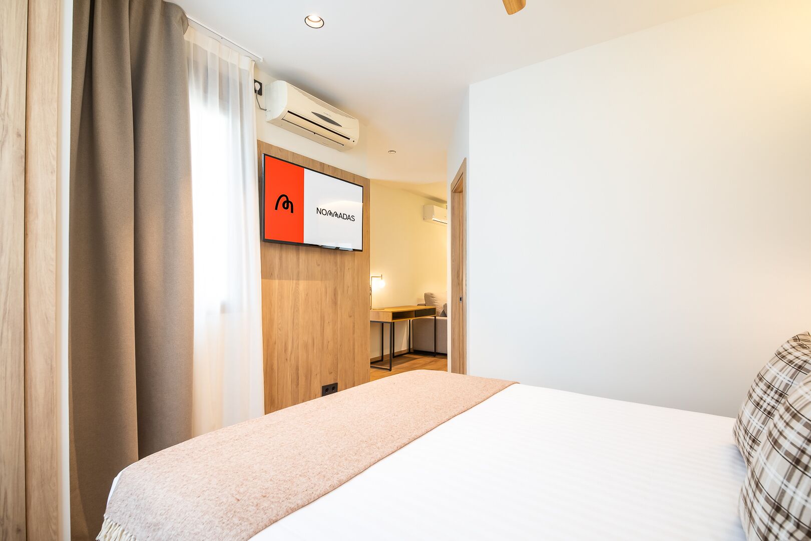 Habitació d'hotel amb un llit, escriptori i aire condicionat.