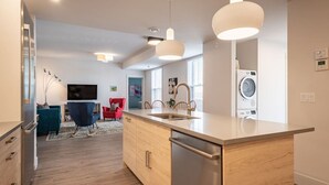 A modern kitchen with a central island, stainless steel appliances, and pendant lighting. - Suite 202- Two Bedroom apartment-style Suite w Balcony in Hybrid Hotel Wolfville (Wolfville)