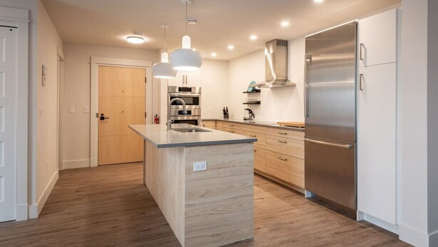 A modern kitchen with a central island, stainless steel appliances, and pendant lighting. - Suite 202- Two Bedroom apartment-style Suite w Balcony in Hybrid Hotel Wolfville (Wolfville)