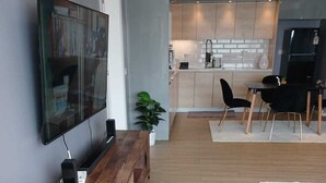 Ett modernt vardagsrum med en träbänk, en platt-TV och en stor krukväxt.