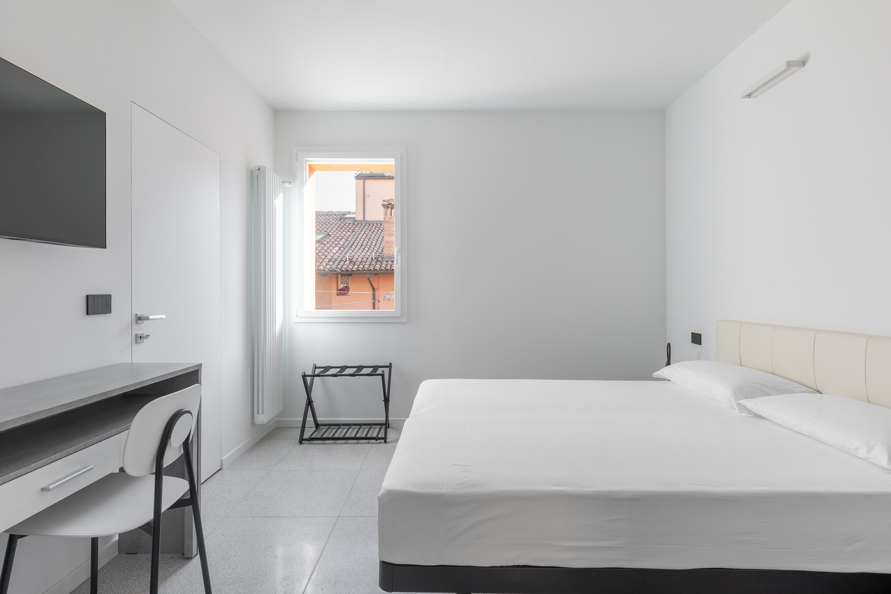 A modern, minimalist room with a bed, a desk, and a chair.