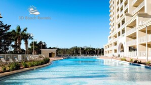 A large, clear swimming pool with lounge chairs and a building with multiple balconies in the background. - Ariel Dunes II 803 *Beach views* 3 pools* (miramar beach)