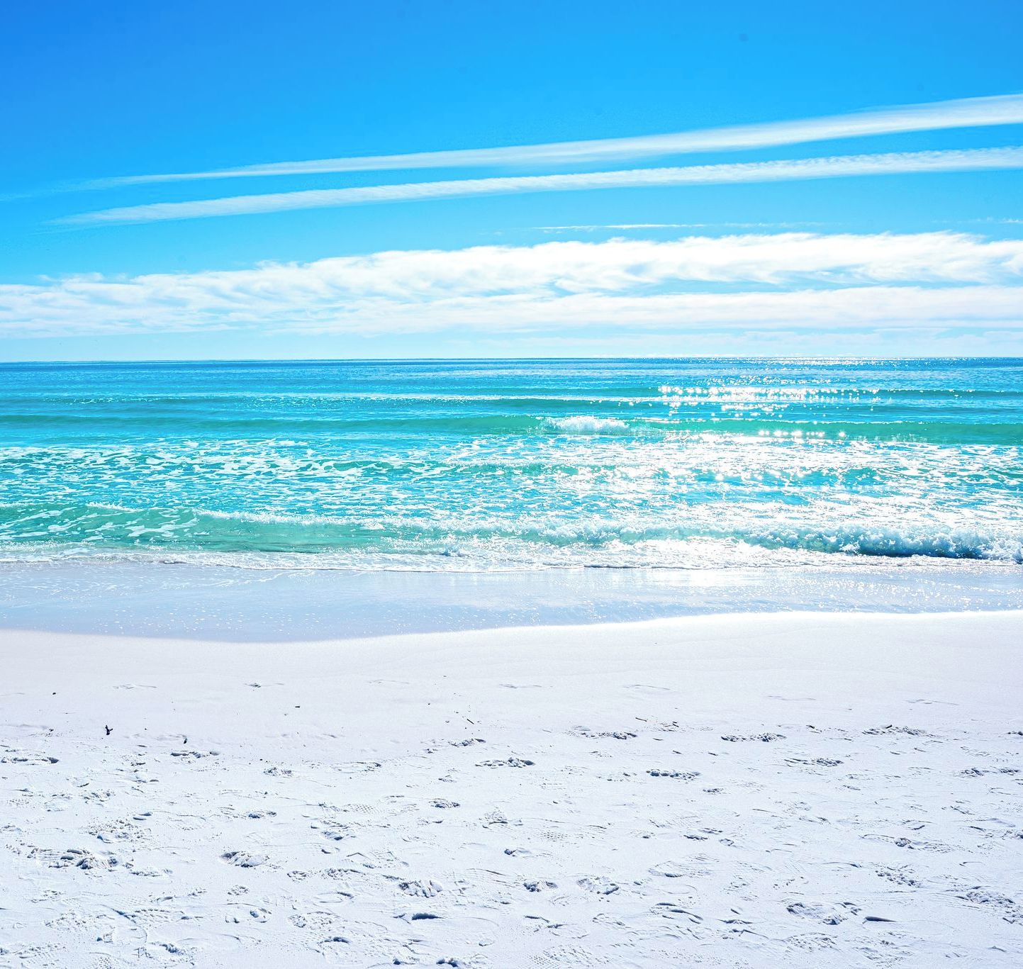 Ein Strand mit klarem türkisblauem Wasser und weißem Sandstrand.