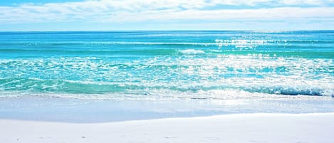 Une plage aux eaux turquoise et cristallines, bordée d’un rivage de sable blanc.