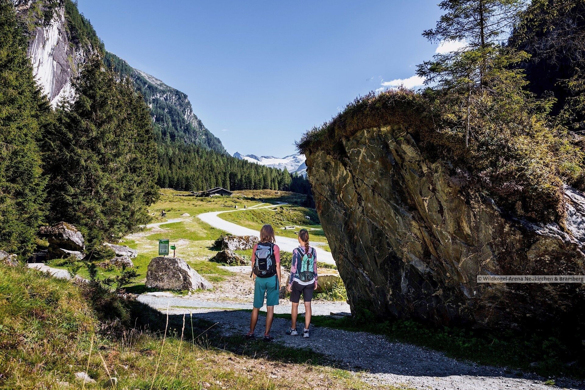 Zwei Wanderer auf einem Pfad mit Bergblick.