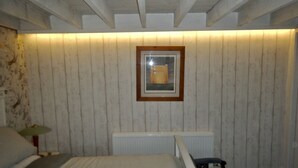 Ein Zimmer mit einem Bett, einem Heizkörper, einem gerahmten Bild an der Wand und einem Fenster mit Jalousien.