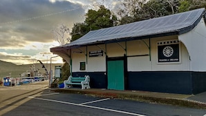 Ein kleines, eingeschossiges Gebäude mit einer grünen Tür und einem Schild mit der Aufschrift 'Bantry Bay Steamship Company Office'.