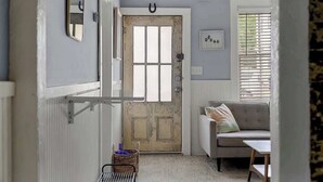 Un couloir avec une porte en bois rustique, un banc rembourré et une petite table.