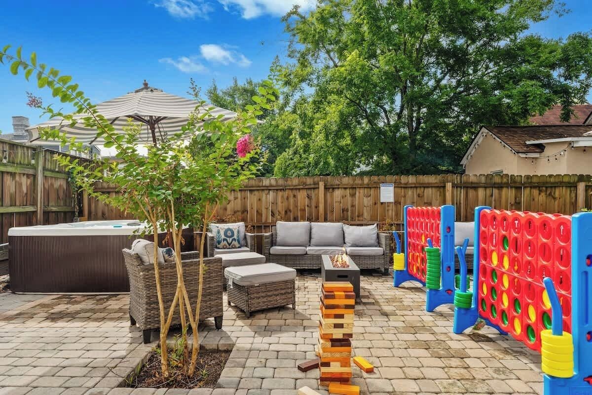 A backyard with a hot tub, outdoor furniture, a wooden fence, and a wooden play structure.