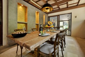 Un comedor con una larga mesa de madera, sillas y una lámpara colgante moderna.