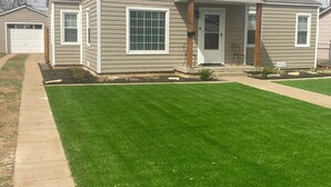 A two-story house with a front porch, a garage, and a well-maintained lawn.