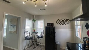 A compact kitchen with a black refrigerator, a microwave, and a stove. There is a dining area with a table and chairs.