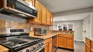 Eine moderne Küche mit Holzausstattung, Edelstahlgeräten, Granit Arbeitsplatten und einem eingebauten Backofen.