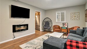 Ein Wohnzimmer mit Flachbildfernseher, Kamin, Sofa, Couchtisch und Sessel.