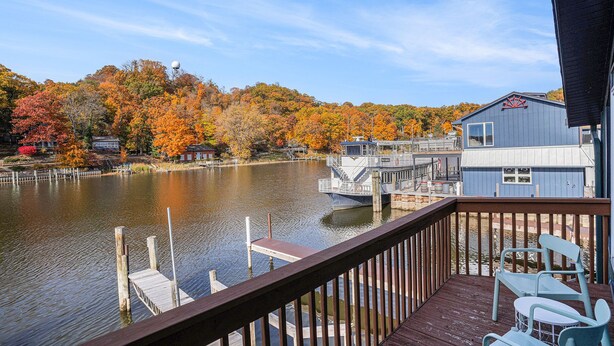 A waterfront property with a dock, a boat, and a view of autumn-colored trees. - Riverfront apartment downtown with parking (Saugatuck)