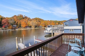 A waterfront property with a dock, a boat, and a view of autumn trees. - Riverfront apartment downtown with parking (Saugatuck)