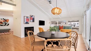 A modern living room with a round dining table, wicker chairs, a fireplace, and artwork on the walls. - Downtown apartment with water view and parking (Saugatuck)