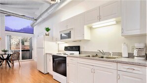 A modern kitchen with white cabinets, a stove, a microwave, and a sink. - Downtown apartment with water view and parking (Saugatuck)