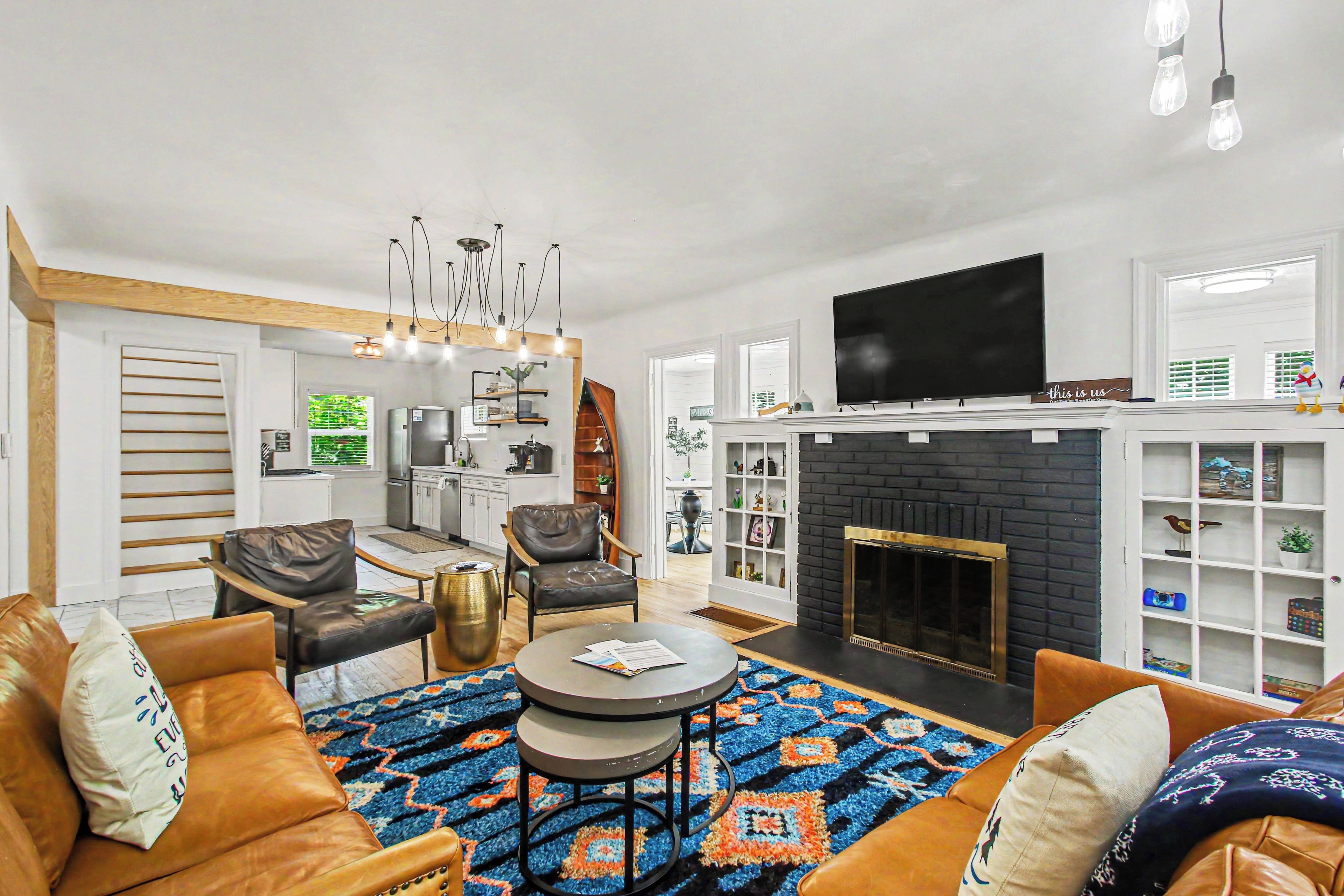 A modern living room with a fireplace, leather sofas, a coffee table, and a dining area.