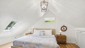 A bedroom with a bed, a window, a wall-mounted light fixture, a bedside table, and a door. - Retreat with hot tub, walking distance to town (Douglas)