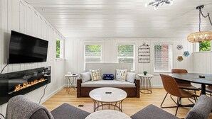 A living room with a fireplace, sofa, coffee table, and dining area. - Retreat with hot tub, walking distance to town (Douglas)