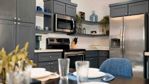 A modern kitchen with grey cabinets, a stainless steel refrigerator, a microwave, and a coffee maker.