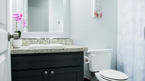 A bathroom with a white sink, dark cabinets, a toilet, and a mirror.