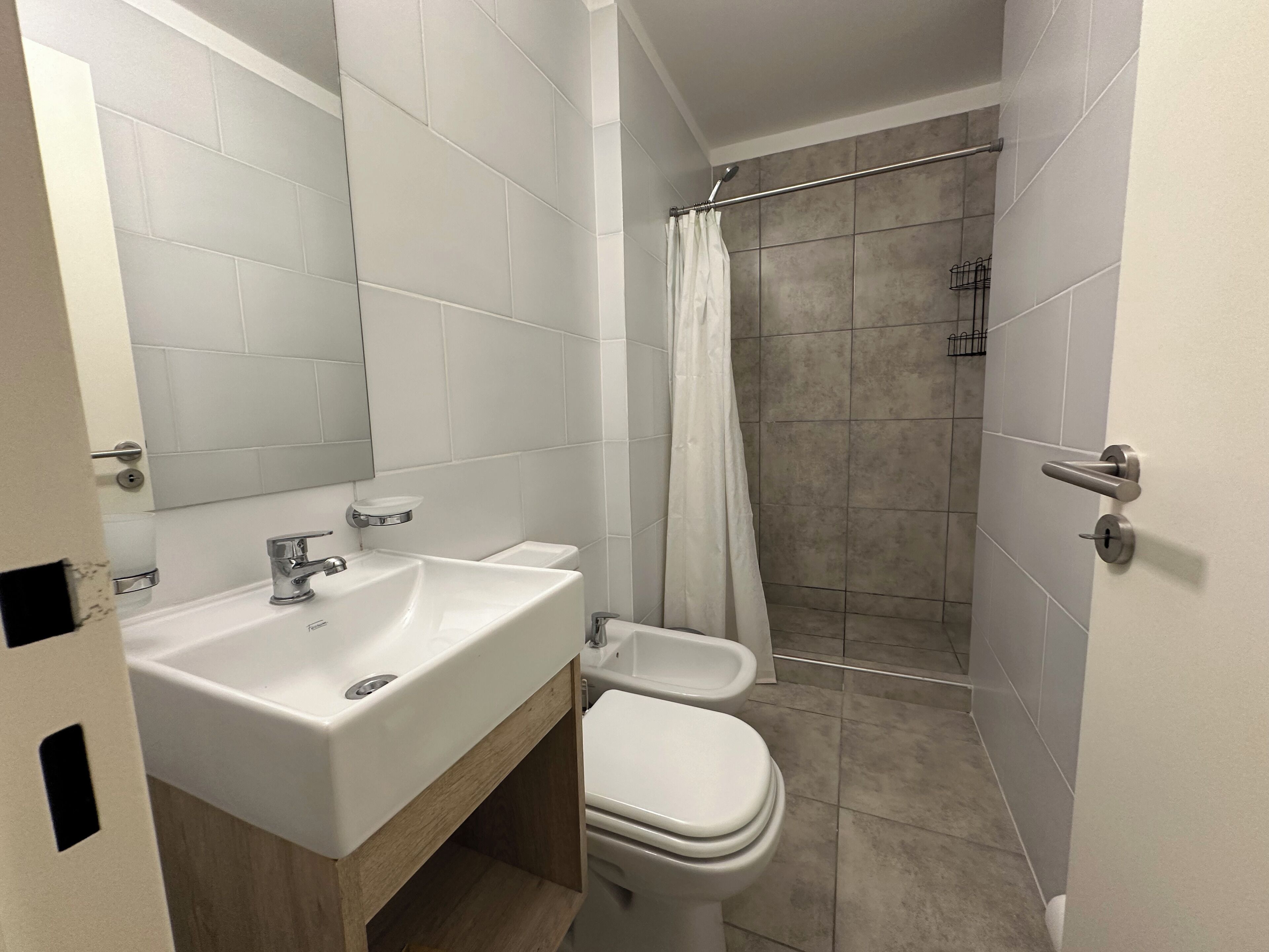 Un baño moderno con lavamanos, inodoro y ducha blancos.