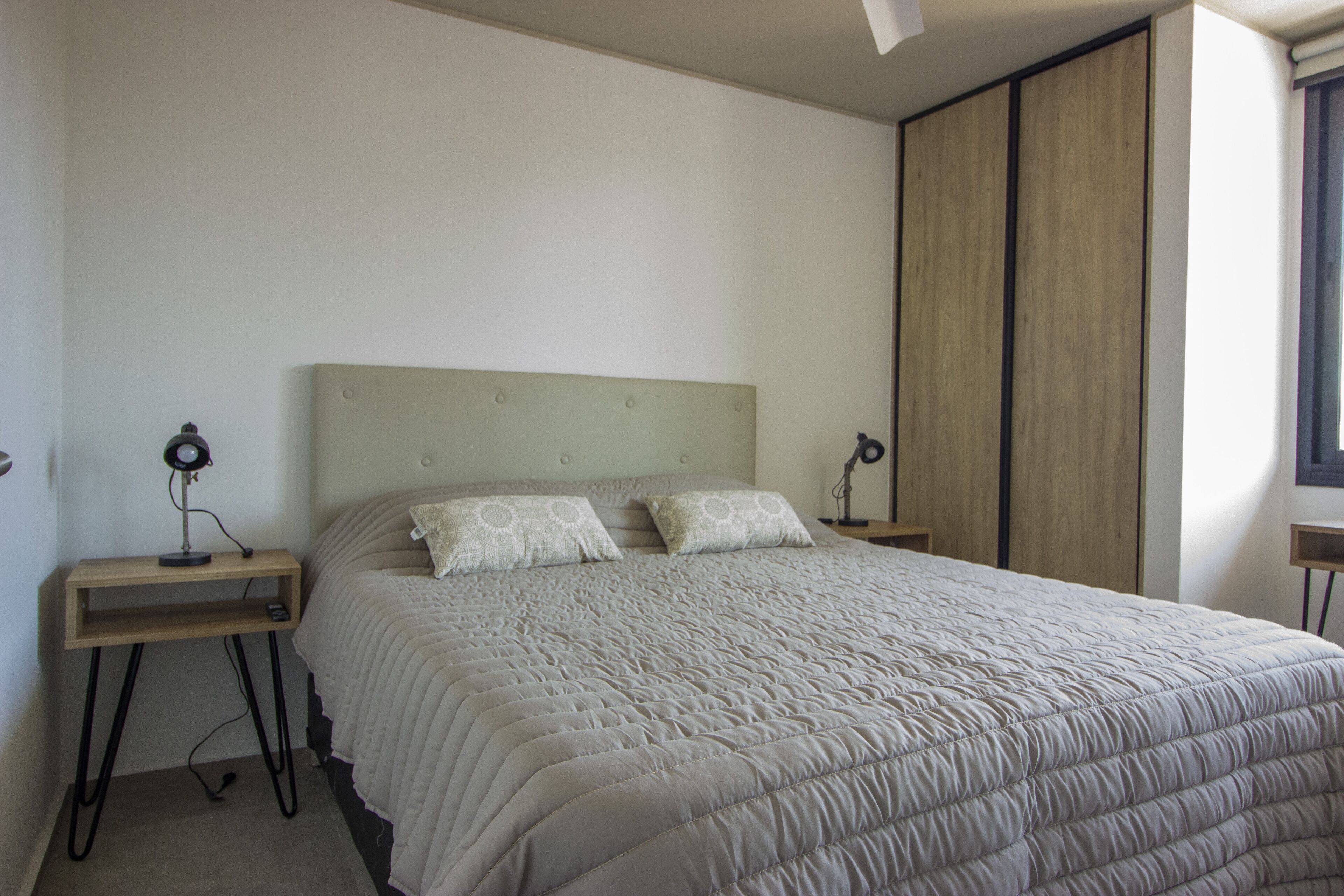 A bedroom with a large bed, two bedside tables, and a wardrobe.