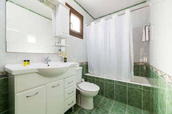 A bathroom with a white sink, toilet, and shower curtain.