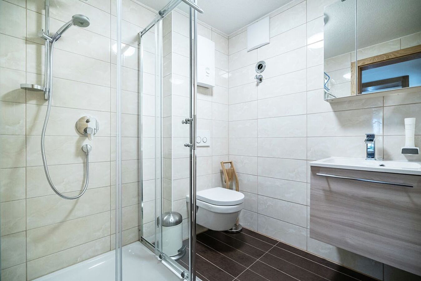 A modern bathroom with a glass shower enclosure, a white toilet, and a vanity with a mirror.