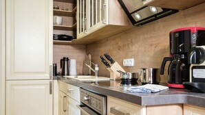 Una cocina moderna con encimera de acero inoxidable, armarios de madera, una cafetera y un juego de cuchillos.