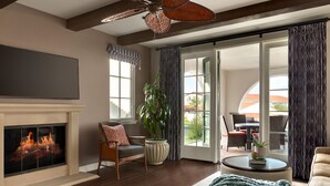 Un salon doté d’une cheminée, d’un ventilateur de plafond, d’un coin repas avec des sièges extérieurs et d’une grande fenêtre.
