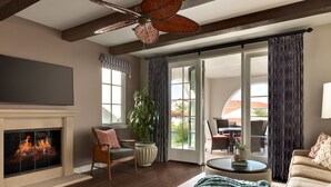 Ein Wohnzimmer mit Kamin, Deckenventilator, großem Fenster und einer Schiebetür zu einer Terrasse.