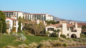 Ein Resort mit mehreren Gebäuden, darunter ein Hotel mit Pool und Meerblick.