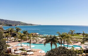 A resort with a large pool surrounded by palm trees and lounge chairs, overlooking a beach and the ocean. - 3 Bedroom Ocean Villa (Rancho Palos Verdes)