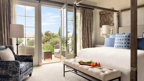 A spacious bedroom with a large bed, a bench with flowers, a chair, and a view of the outdoors through a sliding glass door. - 3 Bedroom Ocean Villa (Rancho Palos Verdes)