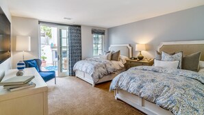 A bedroom with two beds, a desk, and a chair. There is a window with curtains, a door leading to a balcony, and a lamp on the desk. - 3 Bedroom Ocean Villa (Rancho Palos Verdes)
