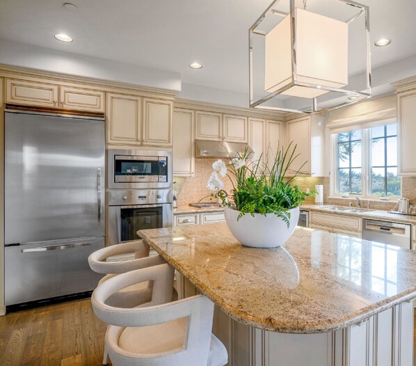 A modern kitchen with stainless steel appliances, a granite countertop, and a large island with bar stools.